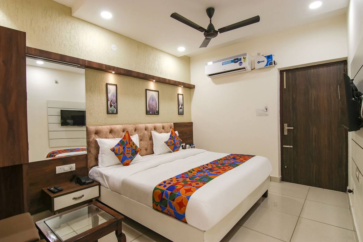 A hotel room with a bed, bedside table, nightstand, and a ceiling fan.