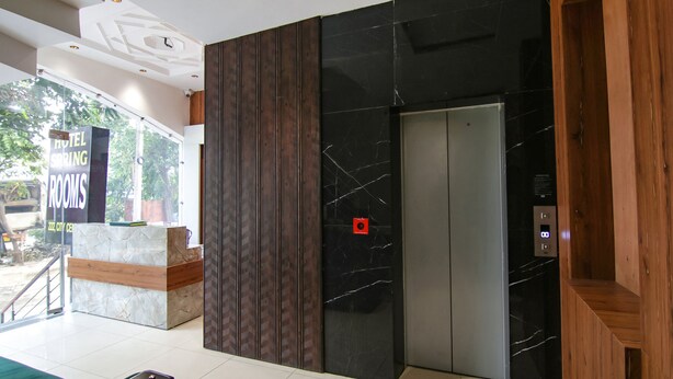 Un vestíbulo de hotel con mostrador de recepción, pared de mármol y un ascensor.