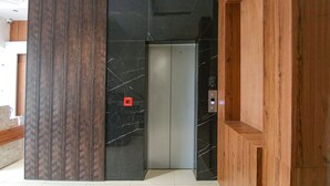 Un ascensor en un edificio moderno con pared de mármol y paneles de madera.