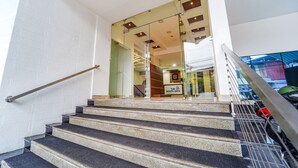 A staircase leading to a building entrance with glass doors and a sign reading "The South Gate." - FabHotel The South Gate (Thiruvananthapuram)