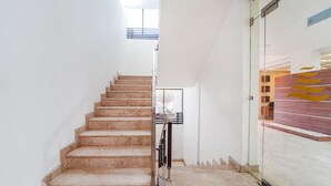 A staircase with a handrail, leading to a room with a glass wall and a wooden floor. - FabHotel The South Gate (Thiruvananthapuram)