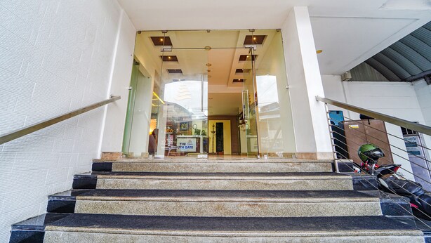A staircase leading to a building entrance with glass doors, a metal railing, and a helmet on the right. - FabHotel The South Gate (Thiruvananthapuram)