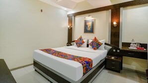 A hotel room with a bed, bedside table, and a mirror. - Fabhotel Prime Three Star (Panvel)