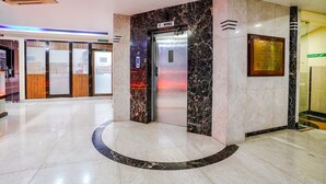 A hotel lobby with a marble reception desk, an elevator, and a plaque on the wall. - Fabhotel Prime Three Star (Panvel)