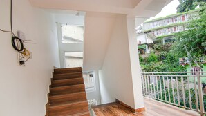 A wooden staircase leading to a balcony with a white railing. - Fabhotel Ayana Inn (Dharamshala)
