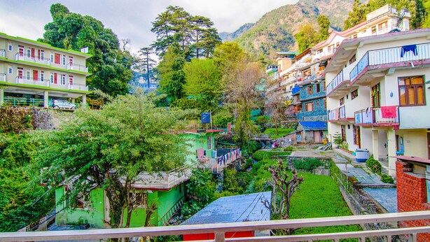 A hillside village with colorful buildings, a green garden, and a visible staircase leading up. - Fabhotel Ayana Inn (Dharamshala)
