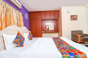 A hotel room with a bed, a chair, a desk, and a mirror. - Fabexpress Shree Shylee Niwas (Chennai)