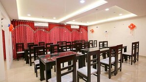 A conference room with multiple tables and chairs, red curtains, and balloons. - Fabexpress Majestic Le Frank (Thiruvananthapuram)