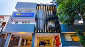 Un hôtel moderne, reconnaissable à son enseigne bien visible « Tab Hotels », doté d’une entrée couverte et devant lequel est garée une voiture.