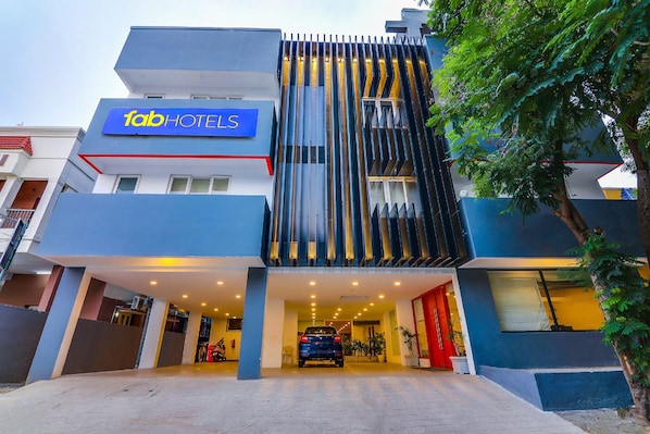 A modern hotel with a prominent 'Tab Hotels' sign, a covered entrance, and a car parked in front.