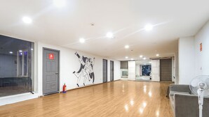 Une pièce spacieuse avec un plancher en bois, une grande fresque murale et une porte ornée d’un panneau d’avertissement.