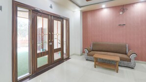 Quarto com porta de vidro deslizante que dá para uma varanda, um sofá marrom e uma mesa de madeira.