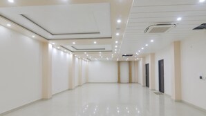 Um corredor amplo e bem iluminado, com design de teto moderno, iluminação embutida e piso brilhante.