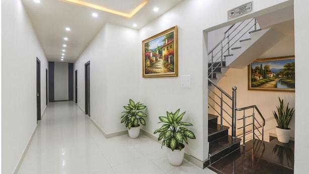 Um corredor de hotel moderno com escada, plantas em vasos e obras de arte nas paredes.