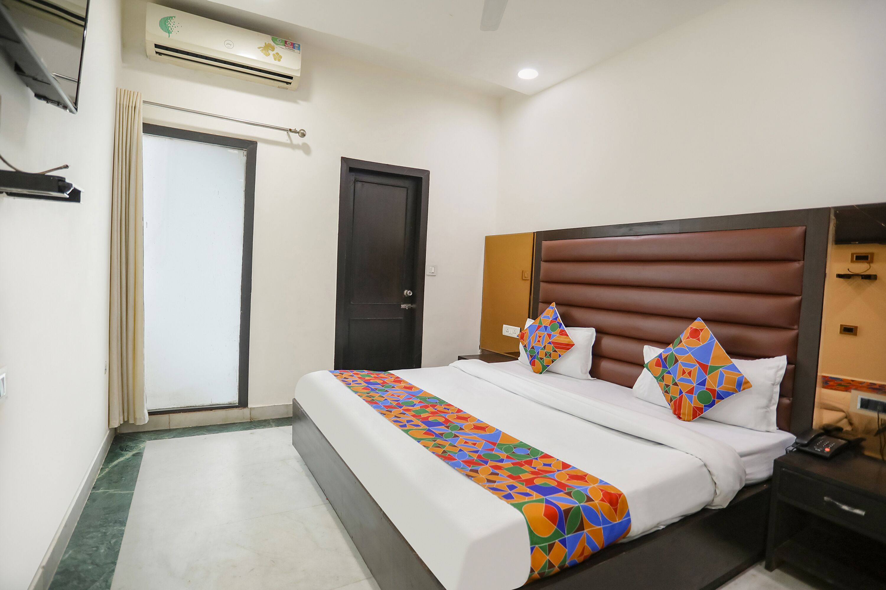 A hotel room with a bed, a nightstand, a desk, and a wardrobe.