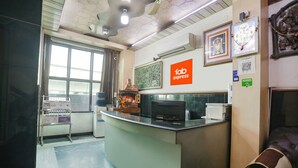 A reception area with a counter, a chair, a window, and a wall with a 'fab express' sign. - Fabexpress The Residency (Noida)