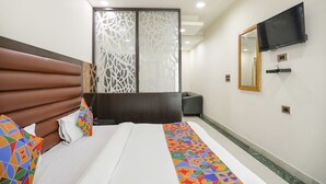 A hotel room with a bed, a TV mounted on the wall, and a decorative partition. - Fabexpress The Residency (Noida)