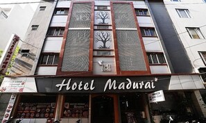 A hotel named "Hotel Madurai" with a modern facade, vertical design elements, and a signboard at the entrance. - Fabhotel Madurai (Udaipur)