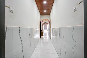 Un couloir aux murs de marbre blanc et au plafond en bois.