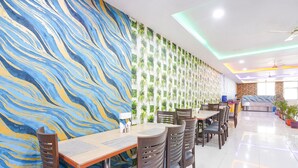 A restaurant with a mural, indoor plants, and a clean, tiled floor. - Fabhotel Prime Syn Grand (Hyderabad)