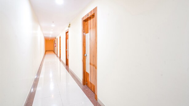 A long, well-lit hallway with white walls and wooden doors. - Fabhotel Prime Syn Grand (Hyderabad)