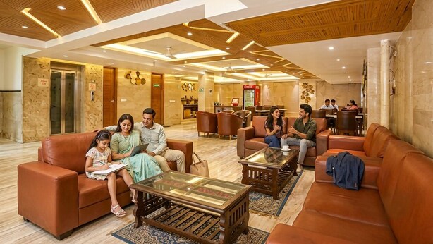 A hotel lobby with leather sofas, a reception desk, and a Coca-Cola refrigerator. - FabHotel Green Lotus Star 17 (New Delhi)