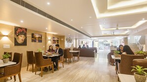 A spacious hotel lobby with a modern design, featuring a central seating area with sofas and tables, a staircase, and a view of the outside. - FabHotel Green Lotus Star 17 (New Delhi)