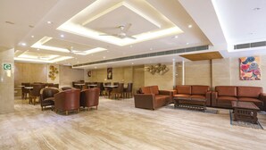 A spacious lobby with a high ceiling, recessed lighting, a central ceiling fan, and a seating area with leather sofas and chairs. - FabHotel Green Lotus Star 17 (New Delhi)