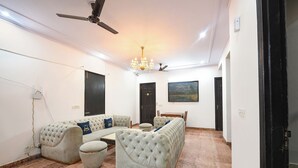Un soggiorno con divano, ventilatore a soffitto, lampadario e un quadro appeso al muro.