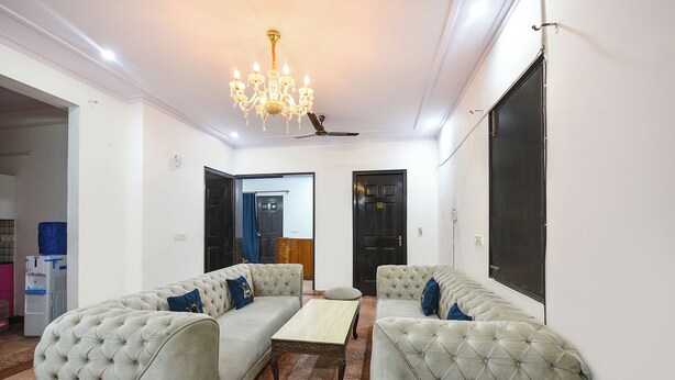 Una stanza con un lampadario, due divani con cuscini blu, un tavolino e una ventola a soffitto.