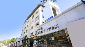 Un hôtel dont la façade porte une enseigne indiquant « HOTEL SHIRDIPARK INN » et « fab hotels ».