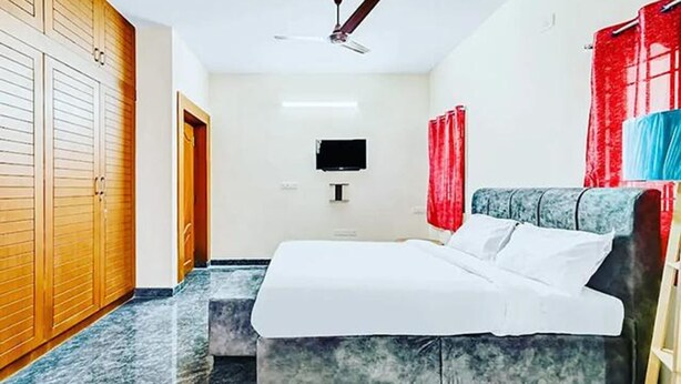 A bedroom with a bed, a ceiling fan, a TV, and a wardrobe. - Fabexpress Aathira Inn (Chennai)