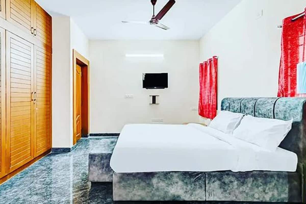 Un dormitorio con cama, ventilador de techo, televisor y armario.
