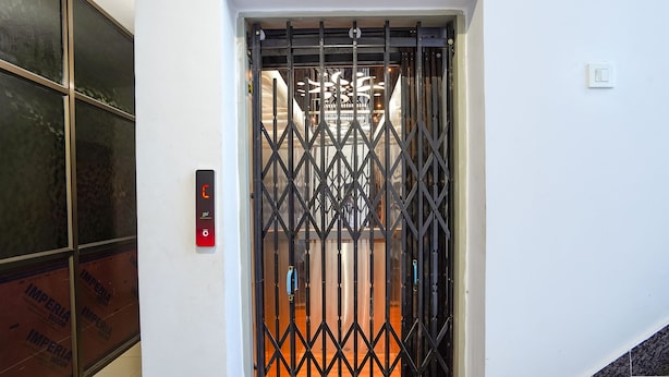 A hotel entrance with a metal gate, a digital elevator control panel, and a tiled wall. - Fabhotel Sk Residency (Varanasi)