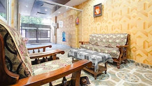 A traditional room with a patterned wall, a wooden sofa, a wooden table, and a bench. - Fabhotel Sk Residency (Varanasi)