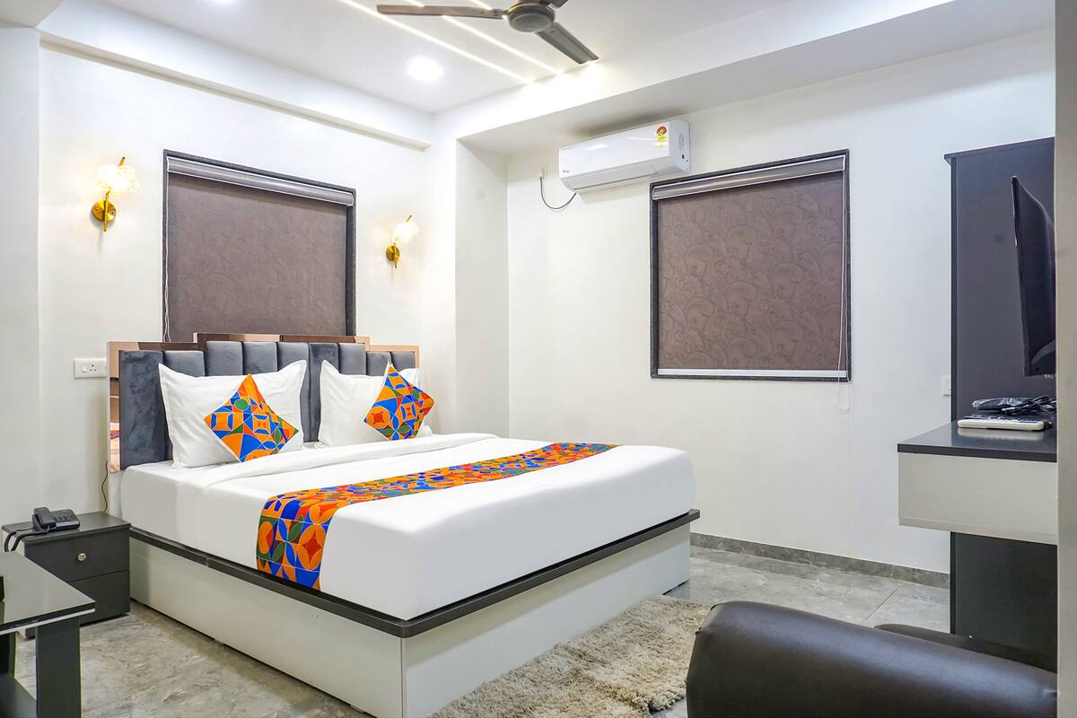 A modern hotel room with a large bed, a desk, and a ceiling fan.