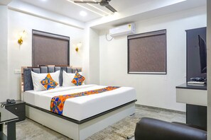 A modern hotel room with a large bed, a desk, and a ceiling fan. - Fabhotel Hill Top Inn (Pune)