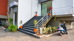 Un edificio con una escalera que conduce a un balcón, rodeado de plantas en macetas.