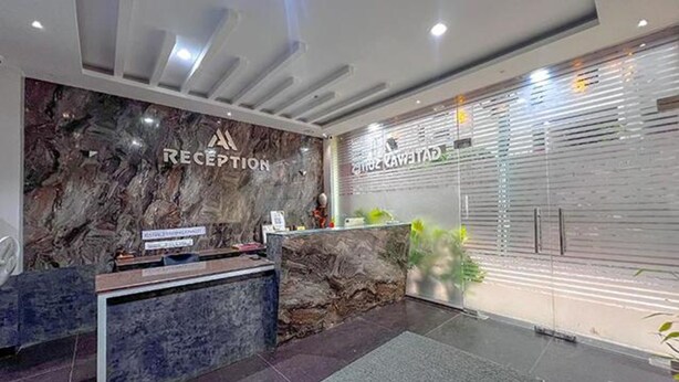 A reception area with a marble wall, a reception desk, and a glass partition with a sign. - Fabhotel Gateway Suites (Bengaluru)