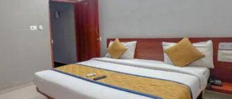 Una habitación de hotel con una cama grande, cabecero de madera y una mesita de noche.