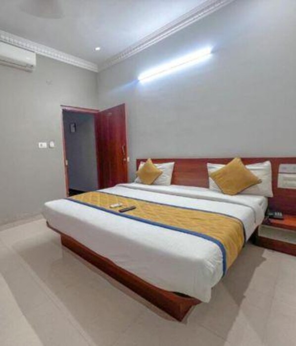 A hotel room with a large bed, wooden headboard, and a bedside table.