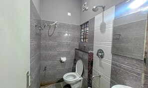 A small bathroom with a toilet, a shower, and a sink.
