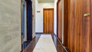 Un couloir doté d’un sol en marbre, de portes en bois et d’un panneau indiquant la sortie.