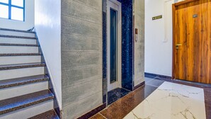 Un hall d’hôtel avec un sol en marbre, une porte en bois et un escalier.