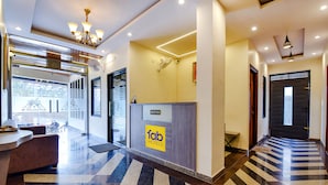 Un hall d'hôtel comprenant un comptoir d'accueil, une enseigne indiquant « Fab Hotels », et un espace d'accueil équipé d'un ventilateur et d'un luminaire suspendu au plafond.
