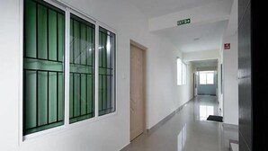 Un couloir propre et bien éclairé, avec une porte sur la gauche et un panneau indiquant la sortie au-dessus.