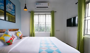 A hotel room with a bed, a window with bars, a mounted TV, and an air conditioning unit. - Fabhotel Majestic Heights (Kanayannur)