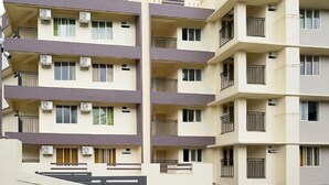 Un immeuble résidentiel à plusieurs étages, doté de balcons, de climatiseurs et présentant un style architectural uniforme.