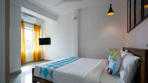 Une chambre d’hôtel équipée d’un lit, d’un téléviseur à écran plat fixé au mur et d’un ventilateur de plafond.