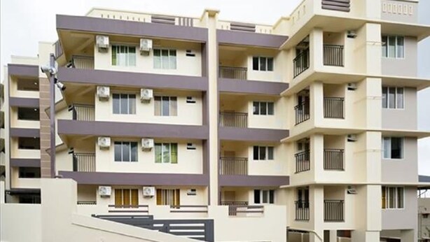 Un immeuble résidentiel à plusieurs étages, doté de balcons, de climatiseurs et d’un toit plat.